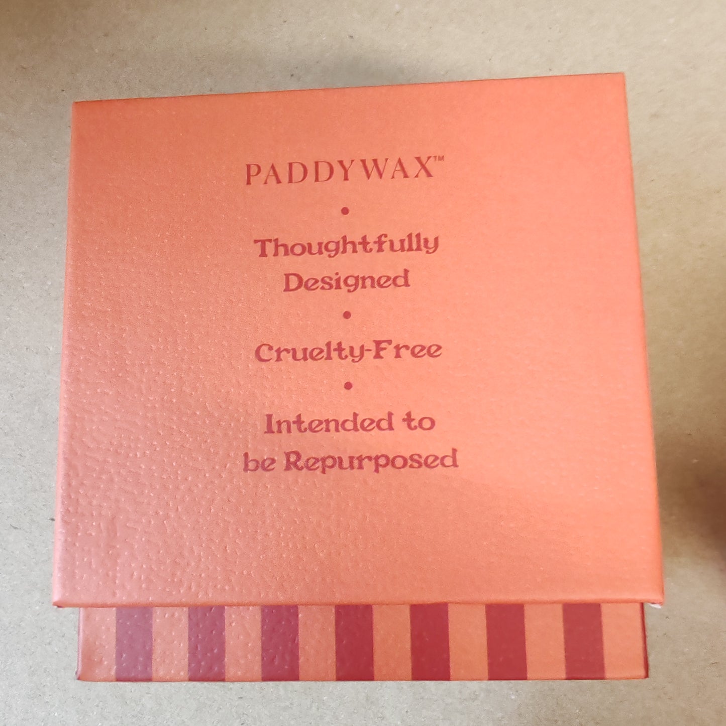 6.5oz scented candle in red and coral stripe ceramic pot. Tangerine and clove